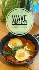 A vlog-style review of a vegan cafe in Hackney, featuring a tour of the interior, outdoor seating, and a taste test of various menu items including coffee, a Mediterranean schiacciata, vegan shakshuka, pastries, and a miso cookie.