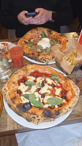 A short, energetic review of Ciaooo Pizzeria in Manchester, highlighting their pizza, sides, and dessert. The video features close-up shots of the food, including the pizza crust and pistachio tiramisu, alongside a voiceover commentary.