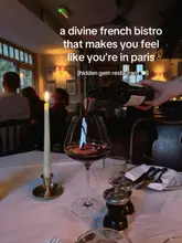 A moody, atmospheric shot of red wine being poured into a glass at a French bistro, capturing an intimate and elegant dining experience.