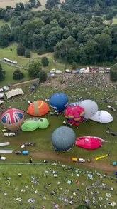 A montage video showcasing the Bristol Balloon Fiesta, featuring various shots of hot air balloons inflating, taking off, and flying over the landscape. The video highlights the scale and beauty of the event, using a mix of ground-level and aerial perspectives to create an immersive experience.