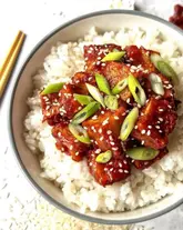 A bright, clean, and highly appetizing overhead shot of a homemade honey gochujang tofu bowl served over white rice, garnished with sesame seeds and spring onions.