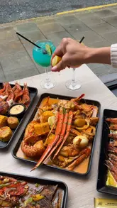 A promotional video for Shrimp & Co, a seafood restaurant in London, featuring close-ups of seafood boils, grilled chicken, cocktails, and the restaurant's interior.