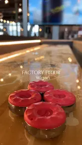 A montage-style video showcasing the Factory Floor venue in Wigan, highlighting its various interactive gaming facilities like shuffleboard, beer pong, and pool, alongside a selection of casual food and cocktails.