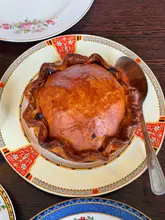 A high-quality, overhead shot of a golden-brown, herb-fed chicken, bacon, and tarragon pie served on a vintage-patterned plate, capturing the rich texture of the pastry.
