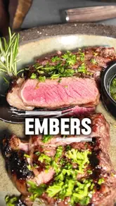 A couple visits Embers restaurant, showcasing their 'Embers Feast' set menu. The video features close-up shots of various dishes including sourdough, grilled broccoli, lamb sausage, sirloin steak, and a Rolo-themed dessert, interspersed with clips of the cooking process and the couple enjoying their meal.
