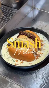 A fast-paced review of Smash N Slide in Greenford, showcasing their range of smash burgers, loaded fries, birria burgers with consommé, and desserts like milk cake. The video highlights the preparation process and the indulgent nature of the food.