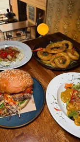 The video is a montage of food and interior shots of The Left Bank in Glasgow, showcasing their new menu and venue look. It features close-ups of various dishes like a chicken burger, chicken satay, and whipped feta, interspersed with shots of the restaurant's interior.