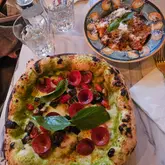 A top-down, overhead shot of a pizza and a pasta dish served on a restaurant table, capturing a casual dinner setting.