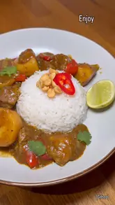 A recipe tutorial video showing the step-by-step preparation of a Thai Beef Massaman curry at home, using a spice blend, diced beef, potatoes, and coconut milk.