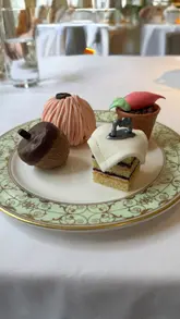 A montage of the Park Room at the Grosvenor House Hotel, featuring the Beatrix Potter themed afternoon tea service. The video highlights the elegant interior, the piano, and the various courses of the tea, including sandwiches, pastries, and scones.