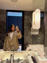 A mirror selfie taken in a modern, marble-tiled hotel bathroom, likely captured during a stay in London as part of a lifestyle or travel content piece.
