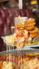 A lively food review vlog featuring two presenters visiting Wavertree Town Hall. They sample a variety of pub-style dishes including a Scotch egg, salt and pepper chicken wings, a sausage roll, gammon steak, a burger, lobster mac and cheese, and sticky toffee pudding, providing commentary on the quality and value of the food.