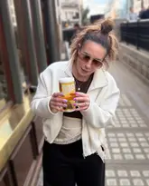 A casual, lifestyle-focused shot of a creator holding a glass of Jubel beer outside a pub, promoting a pub crawl event.