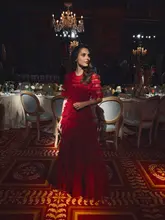 A portrait of a woman in a red dress at a gala event held at a hotel, promoting a partnership with a gin brand.