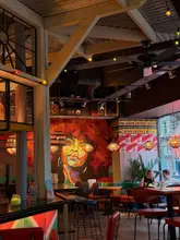 A wide-angle interior shot of a Turtle Bay restaurant, capturing the vibrant, Caribbean-inspired decor, including a large mural, warm lighting, and casual seating arrangements.