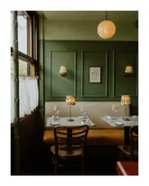 A beautifully composed, symmetrical interior shot of a restaurant booth, showcasing the venue's cozy, upscale aesthetic with warm lighting and elegant table settings.