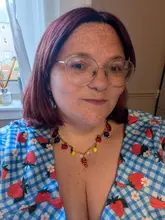 A personal portrait of a creator showcasing a fruit-themed necklace made at a jewellery workshop, highlighting the creative experience.