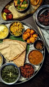 Here are a few options for your SEO alt text, depending on what is visible in the image:

**Option 1 (Focus on the food - best for general shots):**
"A traditional South Indian Thali platter served at Dhamroo restaurant in Headington, Oxford."

**Option 2 (Focus on the atmosphere - best for interior/lifestyle shots):**
"Diners enjoying a sophisticated Indian banquet meal at Dhamroo restaurant in Headington, Oxford."

**Option 3 (Keyword-focused):**
"Authentic South Indian cuisine and Thali banquet served at Dhamroo, a top-rated Indian restaurant in Oxford."

**SEO Tip:** If the image shows a specific dish, make sure to mention the name of that dish (e.g., "Keralan curry platter") in the text.