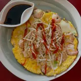 Here are a few options for your alt text, depending on the focus:

**Option 1 (Descriptive & SEO-friendly):**
Vietnamese-style prawn omelette with mushrooms, spring onions, and bean sprouts served with a spicy dipping sauce.

**Option 2 (Action-oriented):**
Homemade Vietnamese-style prawn omelette with fresh herbs and a tangy dipping sauce served for a healthy dinner.

**Option 3 (Concise):**
A healthy, homemade Vietnamese-style prawn omelette with mushrooms and beansprouts and a spicy dipping sauce.

*Tip: Option 1 is generally the best for SEO as it leads with the dish name and includes the key ingredients.*