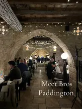 A symmetrical, wide-angle shot of the restaurant interior, showcasing the distinctive stone archways and warm, atmospheric fairy-light lighting that defines the venue's aesthetic.