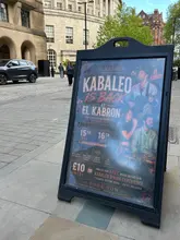 A street-level photograph of a sandwich board advertising a live music and dining event at a Spanish restaurant in Manchester.