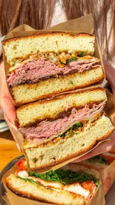 A couple visits Mary's Sandwich Shop in Sandsend, showcasing their popular sandwiches, including the French Dip and The Paulie, while highlighting the coastal location and interior atmosphere.