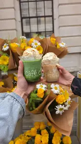 A creator reviews a collaboration drink between Cafe Ciel and Magnolia Bakery, consisting of a matcha latte topped with banana pudding, while standing on the street.