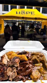 A creator visits Campfield Market in Manchester, highlighting the diverse range of stalls, including art, clothing, and food vendors. The video features a specific review of Caribbean food from Hope Street Kitchen, showcasing dishes like jerk chicken and curry goat, while also capturing the lively atmosphere of the market's indoor and outdoor spaces.