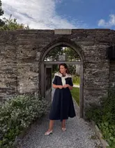 A high-quality lifestyle photograph featuring a creator standing within a rustic stone archway at The Pig at Harlyn Bay. The image captures a relaxed, coastal aesthetic that aligns perfectly with the brand's identity, utilizing natural light and a well-composed frame to highlight the venue's unique architecture.