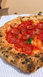 A short, energetic montage showcasing a backyard pizza pop-up venue. The video captures the preparation process, including dough handling and pizza assembly, followed by shots of the finished Neapolitan-style pizzas.