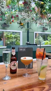 A fast-paced montage showcasing a bottomless brunch experience at The Lawn Club. The video highlights the venue's floral interior, a variety of cocktails, and several sharing-style food dishes, capturing a lively social atmosphere.