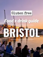 An atmospheric, high-quality sunset shot of the Bristol harbourside, serving as a cover image for a gluten-free food and drink guide. The image effectively captures the vibe of the city, using the scenic waterfront to draw the viewer in.