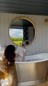 A visually appealing tour of a luxury shepherd's hut accommodation, showcasing the interior living space, the roll-top bath with a view, the outdoor hot tub, firepit, and a breakfast in bed service.