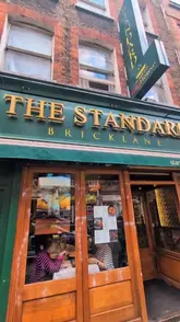 A creator visits The Standard in Brick Lane, providing a tour of the venue's interior and showcasing a variety of Bangladeshi dishes including starters, mixed grills, and curries.