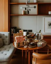 A high-quality, lifestyle-focused shot capturing an in-room hospitality experience at a luxury hotel. The image features a well-curated table setup including popcorn, snacks, a chocolate cake, and a wine bucket, suggesting a cozy, premium movie night or relaxation setting. The composition is balanced and inviting, highlighting the attention to detail in the hotel's service.
