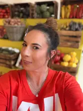 A bright, clear portrait of a creator posing in front of a produce display, promoting the return of a specific salad at a restaurant chain.