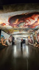 A promotional video showcasing an immersive art exhibition of Michelangelo's Sistine Chapel paintings, featuring two creators walking through the space.