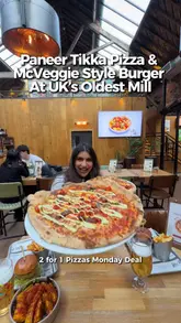 A creator visits The Rolling Mill in Birmingham to review their fusion menu, specifically highlighting the Paneer Tikka Pizza and McVeggie-style burger. The video features shots of the food preparation, the venue's interior, and mentions a 2-for-1 pizza deal on Mondays.