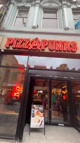 A montage video showcasing the new menu at Pizza Punks in Liverpool, featuring shots of the venue's neon-lit interior, a cocktail, chicken wings, and two different pizzas.