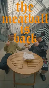 A video showcasing the preparation of a meatball sub, featuring two creators trying the sandwich.