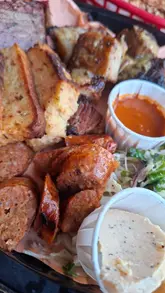 Here are a few options for your SEO alt text, keeping under the 125-character limit:

* **Option 1 (Descriptive):** Loaded barbecue platter at Ringwood Railway featuring a brisket burger, chicken wings, and spice bag fries.
* **Option 2 (Action-oriented):** A delicious spread of local barbecue, including a brisket burger and wings, served at Ringwood Railway.
* **Option 3 (Concise):** Gourmet barbecue platter with locally sourced brisket burger and wings at Ringwood Railway.