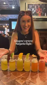 A creator visits TGI Fridays to review their new 'Margarita Maynia' promotion, featuring a flight of six different flavoured margaritas in collaboration with Pantalones Tequila, followed by a meal of chicken strips and pasta.