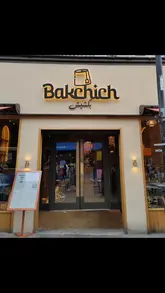 A visual tour of Bakchich, a Lebanese restaurant, featuring shots of the exterior, the menu, and various dishes including spring rolls, hummus, halloumi tacos, and a mixed grill platter, set to music with text overlays.