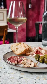 A creator visits Kask wine bar to sample a charcuterie board paired with wine, highlighting the quality of the meats and the EU-funded FICT campaign.