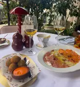 A high-quality, well-composed shot of a table setting at an Italian restaurant in Mayfair, featuring arancini and carpaccio, showcasing an elegant and inviting dining atmosphere.