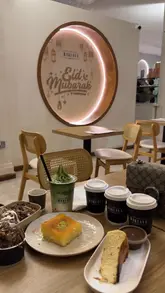 A short montage featuring a table spread of desserts, including baklava, a chocolate cake, and a matcha latte, followed by a close-up shot of chocolate sauce being poured over a cake.