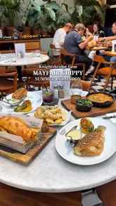 A high-quality montage of various dishes served at Mayfair Chippy, including oysters, truffle fries, prawns, a lobster roll, shepherd's pie, grilled seabass, and traditional fish and chips. The video highlights the presentation and freshness of the food within a stylish, airy venue setting.