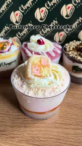 A short, simple product showcase of a Battenberg-flavored cheesecake in a cup, featuring a spoon digging into the dessert to reveal the texture.