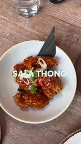 A review-style vlog featuring a visit to Sala Thong in Cambridge. The creator showcases the interior, the menu, and several dishes including Sriracha chilli wings, stir-fried pork belly, and stir-fried vegetables with noodles. The video provides a personal perspective on the dining experience, including pricing and taste impressions.