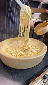 A short, casual vlog-style video featuring a visit to Dirty Gnocchi in Cardiff Market. The creator showcases the preparation of pasta in a large cheese wheel, followed by a taste test of the beef ragu pasta and an arancini ball.